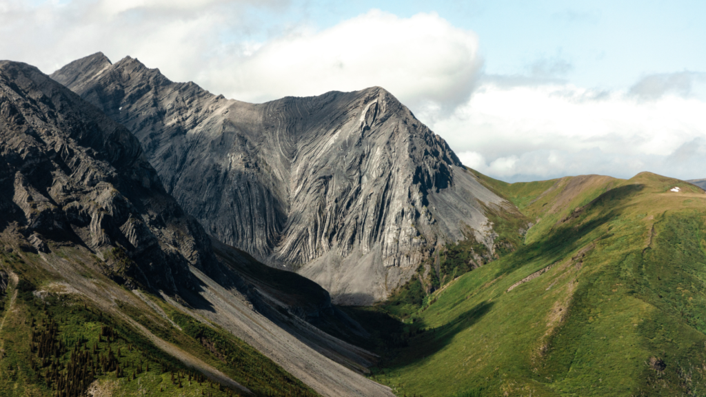 ID: Mountain peak with clear geological lines and grassy slopes 