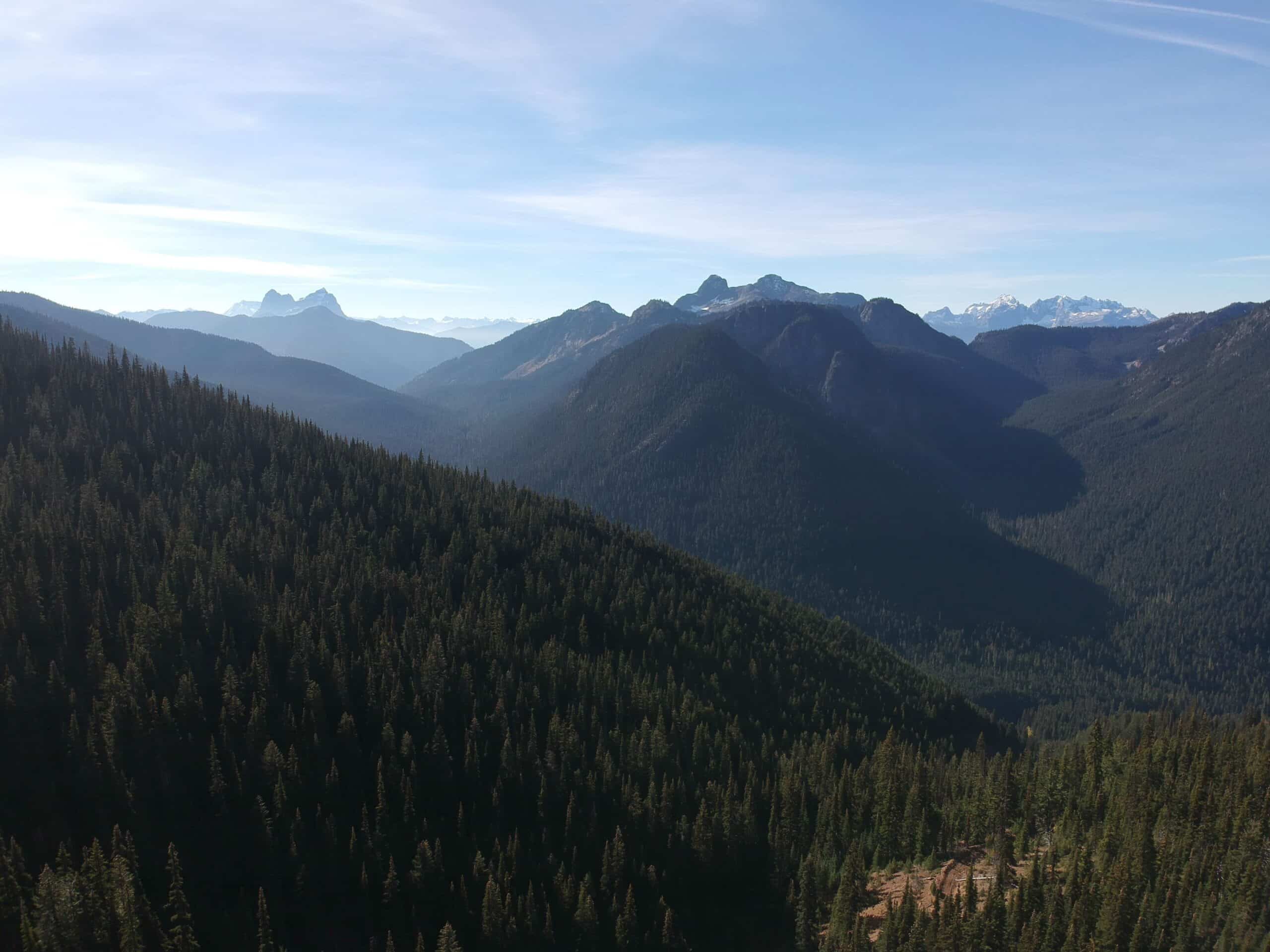 ID: Forested mountains plunge into river valley on blue skied day